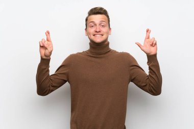 Parmakları geçiş ve en iyi dilek ile izole beyaz duvar üzerinde Blonde adam