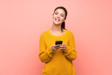 Cep telefonu ile bir mesaj göndererek izole pembe duvar üzerinde Genç kız