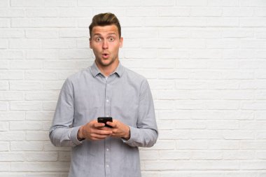 Beyaz tuğla duvar üzerinde sarışın adam şaşırttı ve bir mesaj gönderme