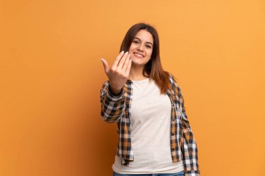 Kahverengi duvarın üzerinde genç bir kadın, benimle gelmek için davet ediyor. Gelmene sevindim.