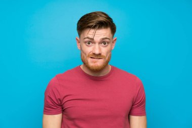 Izole mavi duvarda Redhead adam şüpheleri olan ve yüz ifadesi karıştırmayın