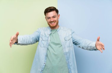 Renkli arka plan üzerinde Redhead adam sunan ve el ile gelmek için davet