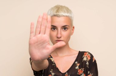 İzole edilmiş duvarın üstünde genç bir kadın elleriyle jesti durduruyor.