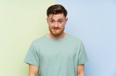 Renkli arka plan üzerinde Redhead adam şüpheler ve yüz ifadesi karıştırarak sahip