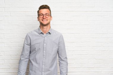 Gözlük ve mutlu beyaz tuğla duvar üzerinde Blonde adam