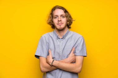 Kollarını ön pozisyonda geçti tutarak izole sarı arka plan üzerinde Blonde adam