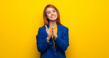 Trençkotlu genç kızıl saçlı kadın bir konferanstan sonra alkışlıyor.