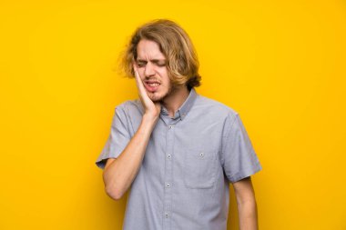 Diş ağrısı ile izole sarı arka plan üzerinde Blonde adam