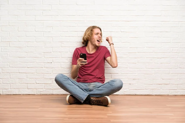 Uomo Biondo Seduto Sul Pavimento Con Telefono Posizione Vittoria — Foto Stock