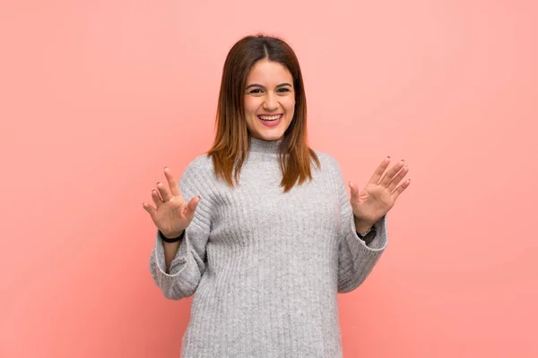 Young woman over pink wall smiling
