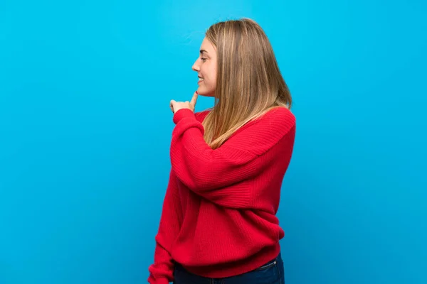 Mujer Con Suéter Rojo Sobre Pared Azul Apuntando Hacia Atrás —  Fotos de Stock