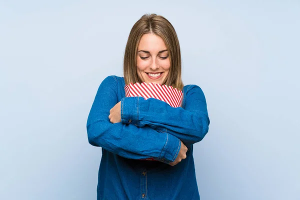 Mulher loira feliz com pipocas sobre parede azul — Fotografia de Stock