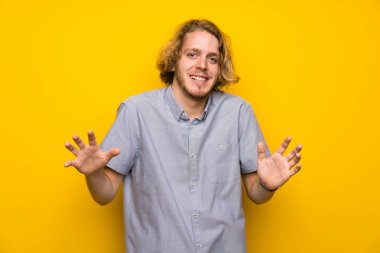 Izole sarı arka plan üzerinde Sarışın adam gülümseyerek