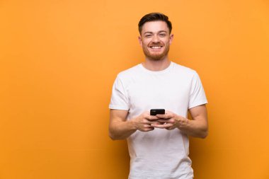 Kahverengi duvar üzerinde Redhead adam cep ile bir mesaj gönderme