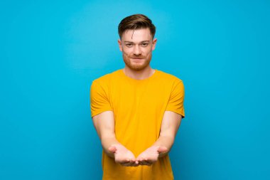Mavi duvar üzerinde Redhead adam bir reklam eklemek için avuç üzerinde copyspace hayali tutan