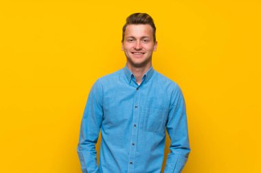 Sarışın adam gülüyor izole sarı duvar üzerinde