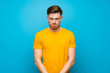 Üzgün ve depresif ifade ile mavi duvar üzerinde Redhead adam