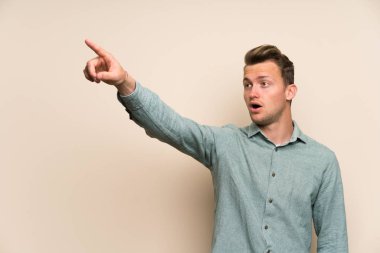 İzole duvar üzerinde sarışın yakışıklı adam uzağa işaret