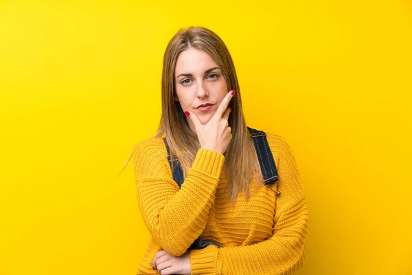 Mulher Com Macacão Sobre Parede Amarela Isolada Pensando Uma Ideia — Fotografia de Stock