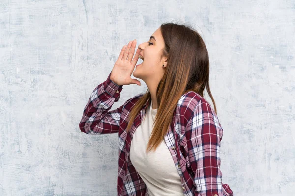 Mujer Joven Sobre Pared Texturizada Gritando Con Boca Abierta —  Fotos de Stock