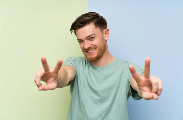 Renkli Arka Plan Üzerinde Redhead Adam Gülümseyerek Zafer Işareti Gösteren — Stok fotoğraf
