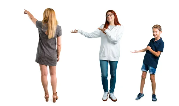 後ろから製品を提示する人差し指で後ろを指す灰色のドレスを持つキッド 若い女の子と中年のブロンドの女性のグループ — ストック写真