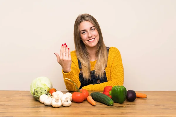 Woman with lots of vegetables inviting to come
