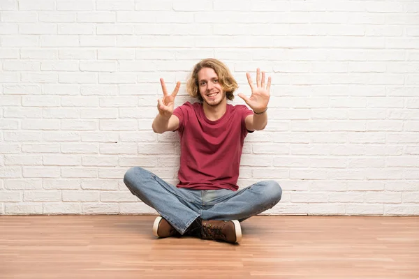 Blonde Man Zittend Vloer Tellen Zeven Met Vingers — Stockfoto