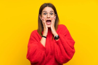 Sürpriz yüz ifadesi ile izole sarı duvar üzerinde genç kadın