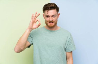 Renkli arka plan üzerinde Redhead adam parmakları ile ok işareti gösteren