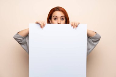 Genç kızıl saçlı kadın, izole edilmiş arka planda, bir konsept eklemek için bir pankart tutuyor.