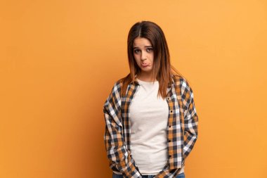 Kahverengi duvarın ardındaki üzgün ve depresif yüzlü genç kadın.