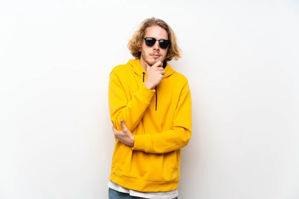 Blonde man with  sweatshirt over white wall with glasses and smiling