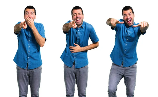 누군가를 손가락으로 가리키고 웃고있는 파란색 셔츠가있는 잘생긴 남자의 — 스톡 사진