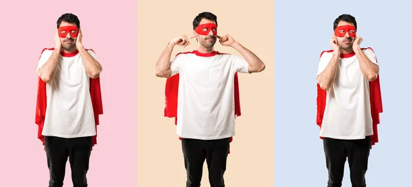 Set of Superhero man with mask and red cape covering both ears with hands on colorful background