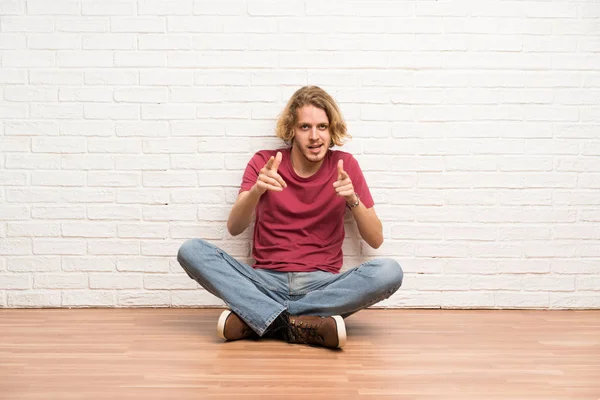 Blonde Man Zittend Vloer Wijzend Naar Voorkant Glimlachend — Stockfoto