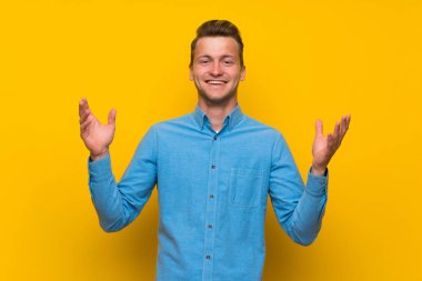 Sarışın adam üzerinde izole sarı duvar çok gülümseyen