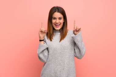 Pembe duvarın üzerindeki genç kadın harika bir fikri işaret ediyor.