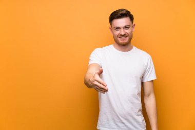 Kırmızı adam iyi bir anlaşma kapanış için el sıkışarak kahverengi duvar üzerinde