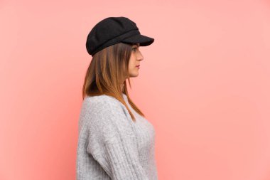 Pembe duvar üzerinde şapka ile Moda kadın kollarını çapraz tutmak ve yan görünümlü