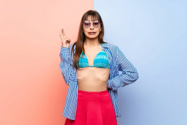 Young woman in bikini with fingers crossing and wishing the best