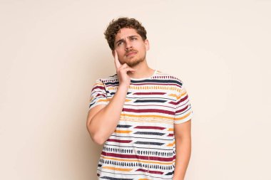 Sarışın adam izole duvar üzerinde yukarı bakarken bir fikir düşünme