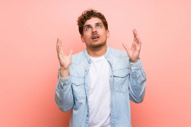 Kötü bir durum tarafından sinirli pembe duvar üzerinde Sarışın adam