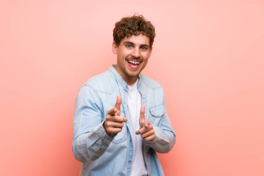 Pembe duvar üzerinde Sarışın adam ön işaret ve gülümseyerek