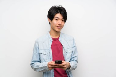 Asyalı adam izole beyaz arka plan mobil ile bir mesaj gönderme