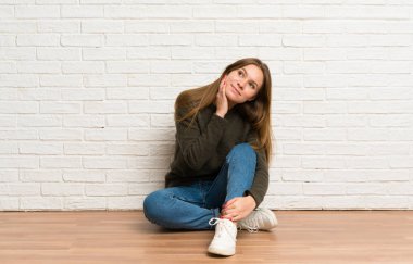 Genç bir kadın yerde oturmuş, yukarı bakarken bir fikir düşünüyor.