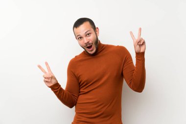 İki eliyle zafer işareti gösteren balıkçı yaka kazak ile Kolombiyalı adam