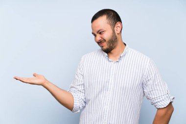 Kolombiyalı adam şüpheile copyspace tutan izole mavi duvar üzerinde