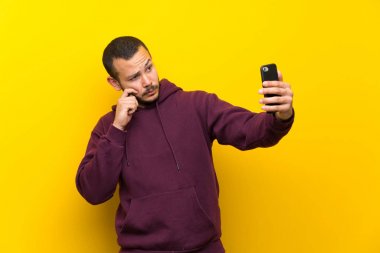 Sarı duvar üzerinde kazak ile Kolombiyalı adam selfie yapıyor
