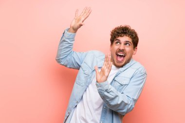 Pembe duvar üzerinde Sarışın adam biraz sinirli ve korkmuş